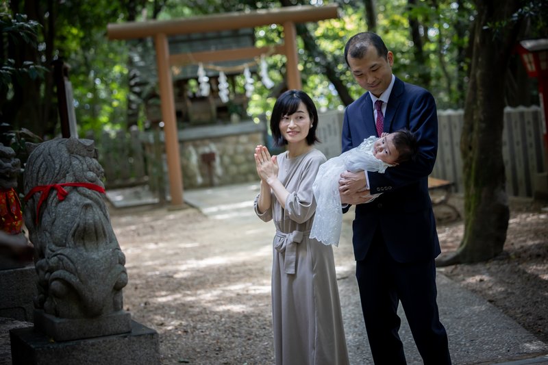 狛犬の前であやされる赤ちゃん